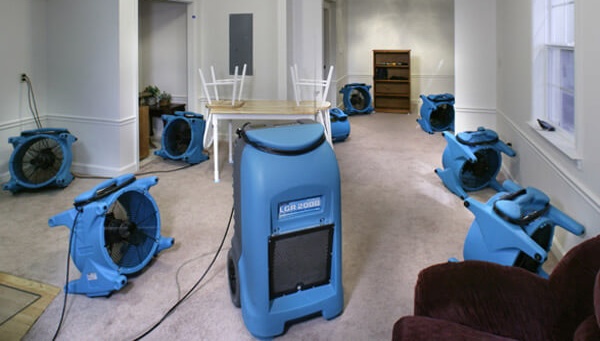Air movers and dehumidification equipment drying a water-damaged room